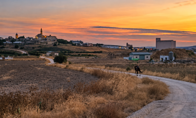 Camino rural de Marchena al atardecer con un jinete y el pueblo al fondo