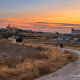 Camino rural de Marchena al atardecer con un jinete y el pueblo al fondo