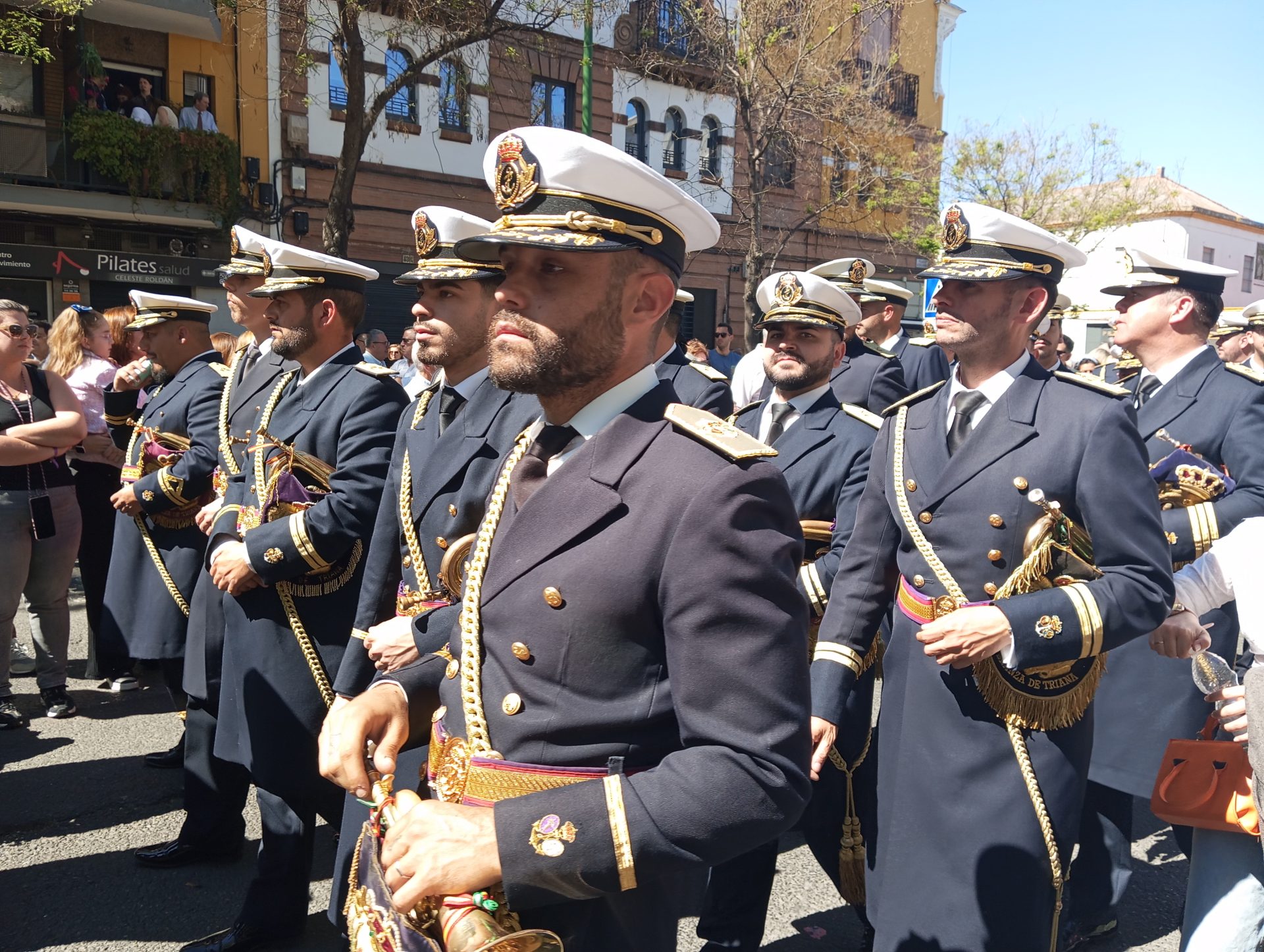 Banda de cornetas y tambores de las Tres Caídas de Triana acompañando una procesión en Sevilla durante la Semana Santa de 2026. Fotografía de Cofrades 2020 sevilla, licencia CC BY 4.0.